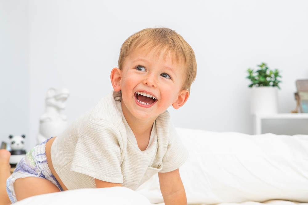 A boy toddler playing on a bed in a diaper at home. 