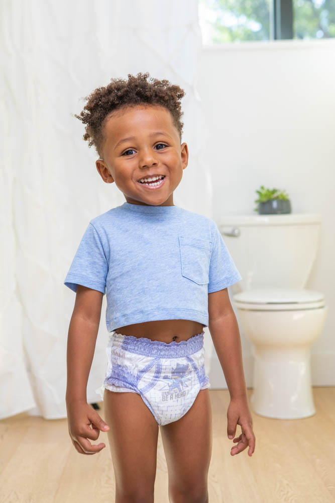 A toddler boy dancing in the bathroom wearing her pamper diaper. 